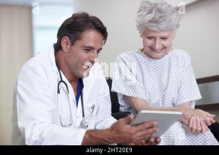 Your tests came back all clear. A male doctor giving his senior patient some good news using his digital tablet. Stock Photo