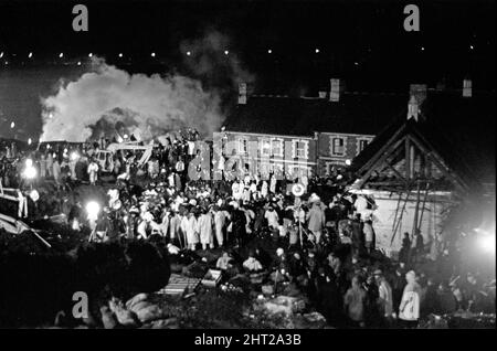 Aberfan, South Wales, circa 21st October 1966 Picture shows the mud and devastation caused when mining spoil from the hillside high above the town behind came down  and engulfed The Pantglas Junior School on 21st October 1966.   Rescuers trying to find victims and help, monist the mud and rubble around the school site, throughout the night  The Aberfan disaster was a catastrophic collapse of a colliery spoil tip in the Welsh village of Aberfan, near Merthyr Tydfil. It was caused by a build-up of water in the accumulated rock and shale, which suddenly started to slide downhill in the form of sl Stock Photo