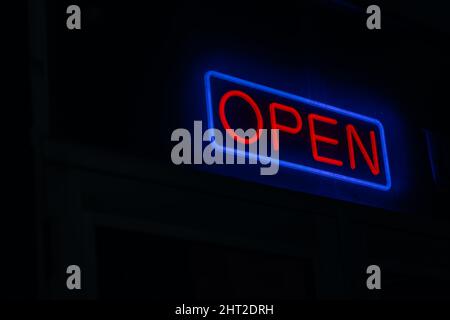 An ''OPEN'' sign with neon letters in a square on a black background Stock Photo
