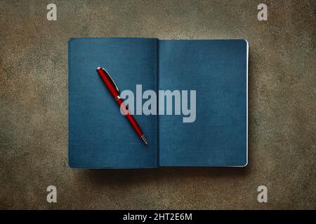 Beautiful red fountain pen rests on textured blue diary, close-up, stylized Stock Photo