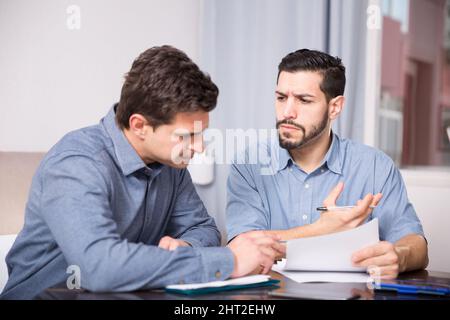 Two serious men with documents at table Stock Photo