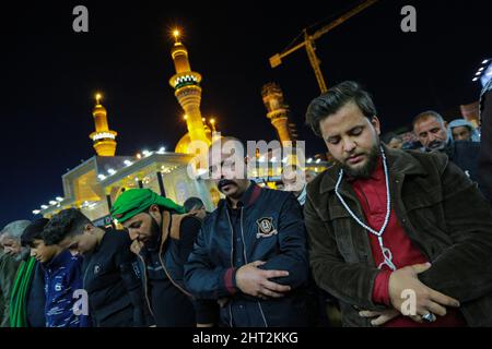 Baghdad, Iraq. 26th Feb, 2022. Shiite pilgrims pray in front of shrine of Imam Musa al-Kadhim, the seventh Imam in Twelver Shia Islam who died at the end of the 8th century, during the annual commemoration of his death. Credit: Ameer Al Mohmmedaw/dpa/Alamy Live News Stock Photo