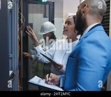 Run me through this again. Shot of two workers inspecting the electronic equipment in a server room together at work. Stock Photo