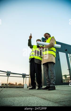 Two senior construction managers are standing while talking about the plans Stock Photo