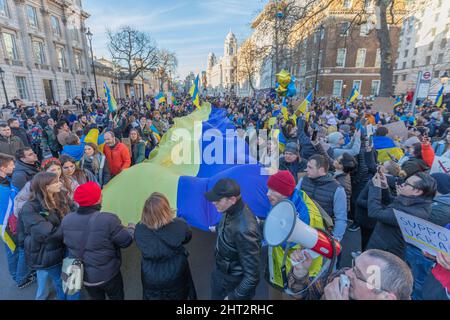 London, UK. 26th Feb, 2022. Protesters walk along Whitehall with a giant Ukrainian flag. Hundreds gather for a protest to show solidarity with Ukraine outside Downing Street. With Ukraine now an occupied country and capital Kyiv under siege from the occupying Russian army, demonstrators come together to stop the attack on the country and support the rights of Ukraine and Ukrainians. Penelope Barritt/Alamy Live News Stock Photo