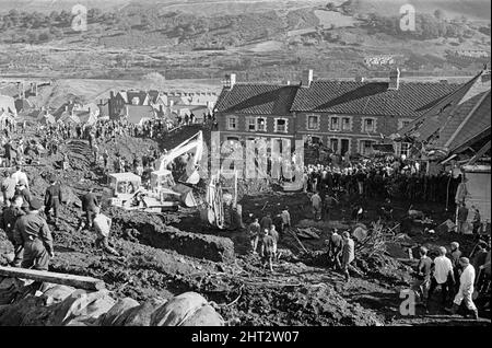 Aberfan, South Wales, circa 21st October 1966 Picture shows the mud and devastation caused when mining spoil from the hillside high above the town behind came down  and engulfed The Pantglas Junior School on 21st October 1966.   Rescuers trying to find victims and help, monist the mud and rubble around the school site.  The Aberfan disaster was a catastrophic collapse of a colliery spoil tip in the Welsh village of Aberfan, near Merthyr Tydfil. It was caused by a build-up of water in the accumulated rock and shale, which suddenly started to slide downhill in the form of slurry and engulfed The Stock Photo