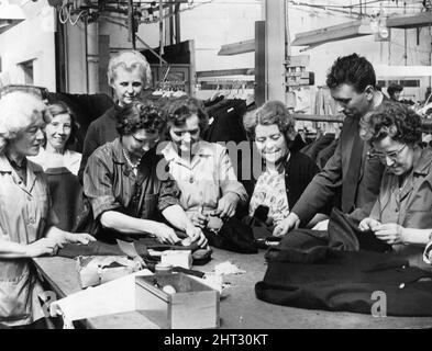 J Harvey Limited Clothing factory in Tredegar, Blaenau Gwent, southeast Wales, Friday 2nd April 1965. The clothing factory which produces duffel coats, jackets and trousers, employs 300 workers, mostly women, and will be taken over by Clifford Williams and Son Limited of Birmingham next week (9th April).  Our picture shows ... Quality Manager, M H Jenkins, inspects the clothing before it is despatched to customers. Third from left at the rear is Mrs H Hayward, personnel officer at the factory. Stock Photo