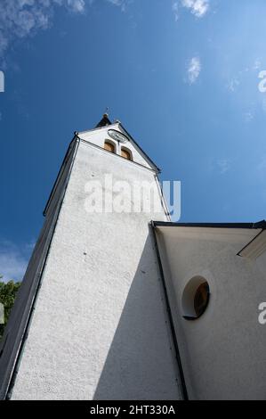 Low angle shot of a white tower of a church against a blue sky on a sunny day Stock Photo