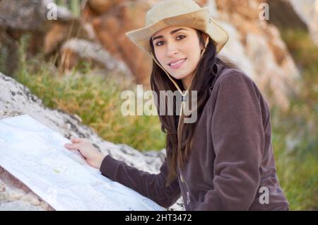 Navigating the hiking trail. A gorgeous young woman in a cowboy hat reading a map outside. Stock Photo