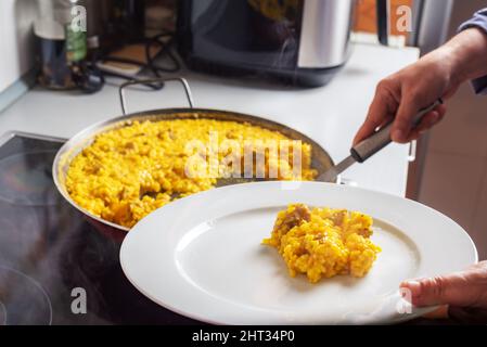 Serving a plate of freshly made paella, only with pork, in the kitchen of a house. Stock Photo