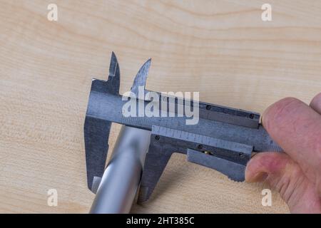 Close up view of hands man  measuring an aluminum pipe with an  calipers isolated. Sweden. Stock Photo