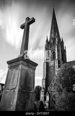 Vertical, grayscale shot of a cross in front of St Martin's Church, Dorking, UK Stock Photo