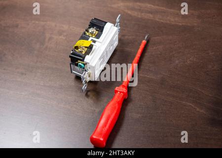 A tested electrical outlet lies on the table before being installed in a junction box on the wall. Stock Photo