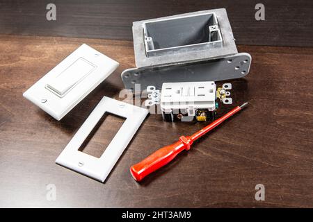 A tested electrical outlet and switch lies on the table before installing it in a junction box on the wall. Stock Photo