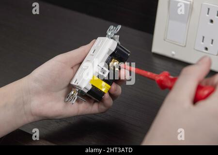 Checking the electrical outlet before installing it in a junction box on the wall Stock Photo