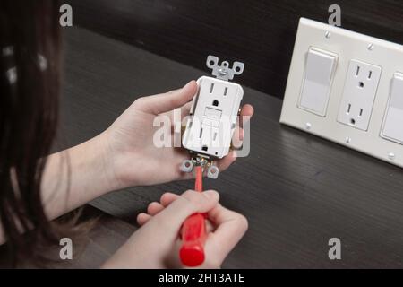 Checking the electrical outlet before installing it in a junction box on the wall Stock Photo