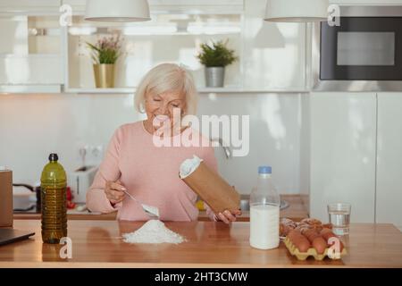 Smiling retired woman enjoying cooking at home Stock Photo