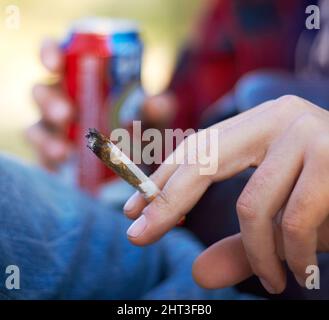 Puffing the day away. Shot of a unrecognizable person smoking a large marijuana joint. Stock Photo