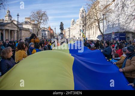 London, UK, 26th Feb 2022 People hold on to a giant Ukrainian flag as thousands have gathered in Whitehall to protest against Russia's recent attack on the Ukraine. Stock Photo