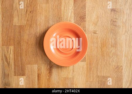A top view of an orange glassy plate on a wooden background Stock Photo