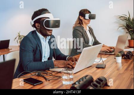 Man with VR headset working on laptop in metaverse Stock Photo