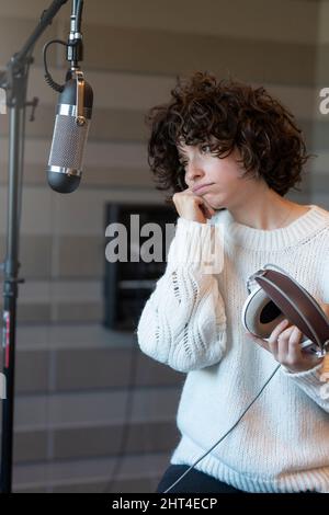 A young curly hair singer woman is worried in the recording studio Stock Photo