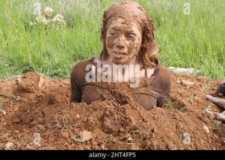A woman buried in the ground A face covered in the ground Stock Photo