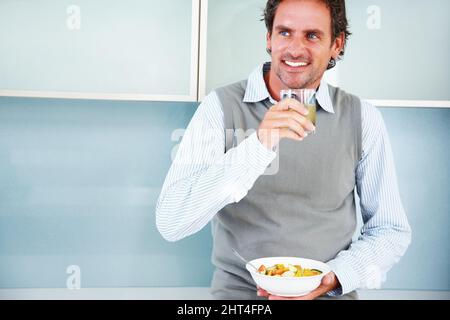 Smiling mature man with appetizer and fruit salad. Smiling mature man looking away with lemon juice and fruit salad. Stock Photo