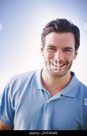 Cool and casual. Portrait of a handsome man smiling happily while standing outside. Stock Photo