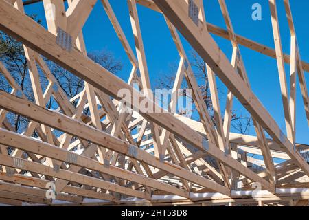 Many wooden roof trusses on a new home construction project with blue sky in the background. Stock Photo