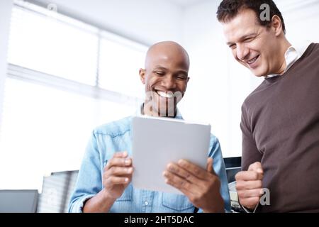 We can check the figures online. Two business colleagues working on a digital tablet in the office. Stock Photo
