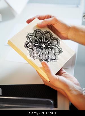 Home craft printing options. Cropped shot of a womans hands holding a wooden craft stamp. Stock Photo