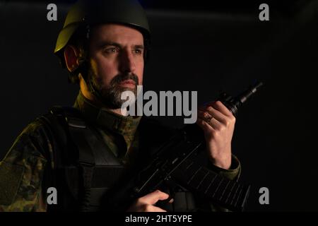 A soldier in military uniform and helmet with weapon on black background. Stock Photo