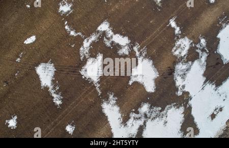 Winter landscape background. Brown earth covered with snow aerial view
