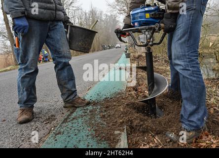 Brandenburg, Germany. 27 February 2022, Volunteers drill a hole for a bucket next to a road where a toad fence will be installed. Now especially the common toads and moor frogs start their migration. As a result of the mild temperatures of the past few days, these animals are slowly becoming active again. As soon as the night temperatures no longer drop below six degrees, the toads, toads, newts, salamanders and frogs begin their spring migration to their ancestral pond waters. Volunteers as well as members of NABU and the nature guard put up toad fences along ma Credit: dpa picture alliance/A