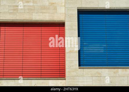 A modern building facade with large windows and shutters in red and blue Stock Photo