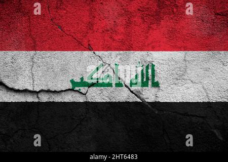 Full frame photo of a weathered flag of Iraq painted on a cracked wall. Stock Photo