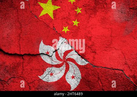 Full frame photo of weathered flags of Hong Kong and China painted on a cracked wall. Stock Photo