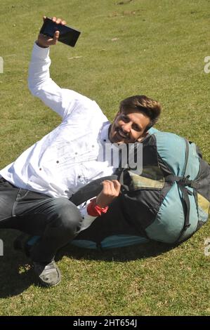 A happy young guy doing fun with lying on Parachute backpack in outdoor Stock Photo