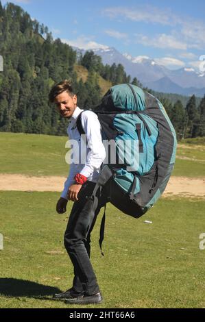 Rear view of a young male tourist walking with carrying parachute bag in the mountain Stock Photo