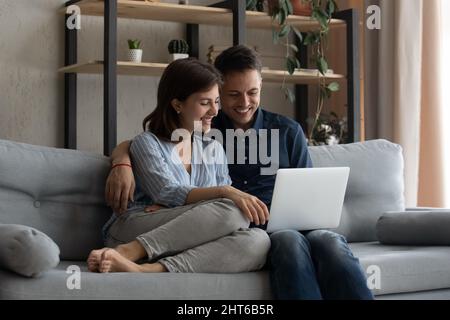 Happy loving couple using laptop at home. Stock Photo