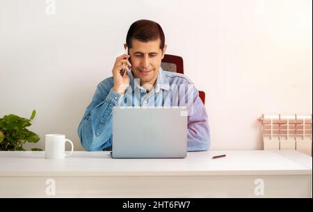 Cropped shot of a handsome young businessman sitting alone in his home office and talking on his cellphone Stock Photo