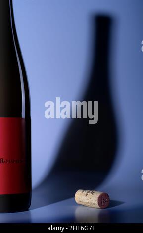 Red wine bottle and plug casting shadow on blue backround Stock Photo