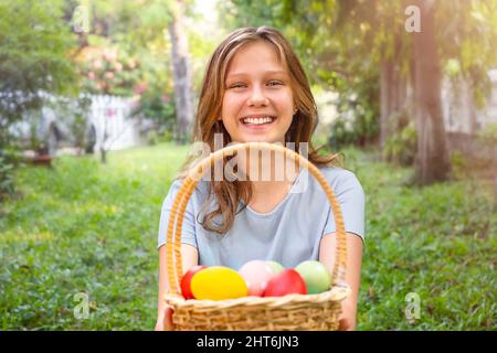 Portrait of a happy teenage girl with a basket of Easter eggs in the backyard Stock Photo