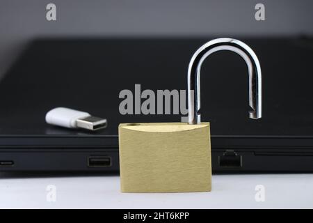 Cyber security or data security concept using a metal lock with a data storage device and laptop on background Stock Photo