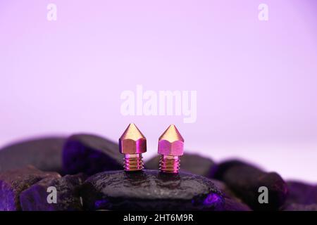 3D printer nozzles for a 3d printer on a stone with dull colorful lights background Stock Photo