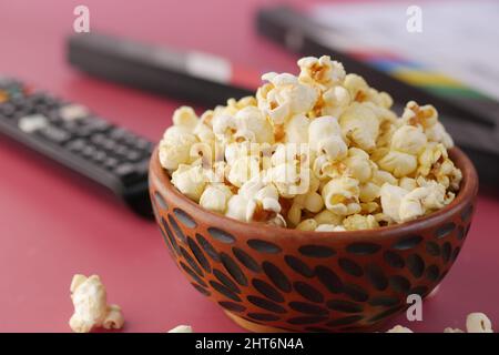 close up of popcorn and Tv remote on red background  Stock Photo