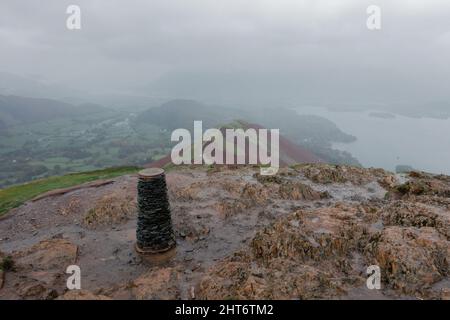 A quiet day on Catbells summit trig point on a wet, rainy and windy day, Lake District, Cumbria, England, UK Stock Photo