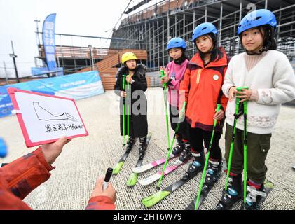 (220227) -- CHENGDU, Feb. 27, 2022 (Xinhua) -- Coach Cao Jian instructs as members of the 'Dieyun' ski team learn at a dry ski training facility in Xindu District of Chengdu, southwest China's Sichuan Province, Feb. 25, 2022. When seeing the boys and girls skiing down the slope, no one will realize they are anything different from other ski-loving youngsters until noticing their coach communicating with them mainly through writing and gesturing.   All of the 15 members of this ski team are students from the special education school in Xindu District of Chengdu, capital city of southwest China' Stock Photo