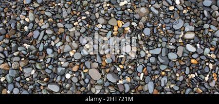Smooth round pebbles texture background. Pebble sea beach close-up, dark wet pebble and gray dry pebble. Stock Photo